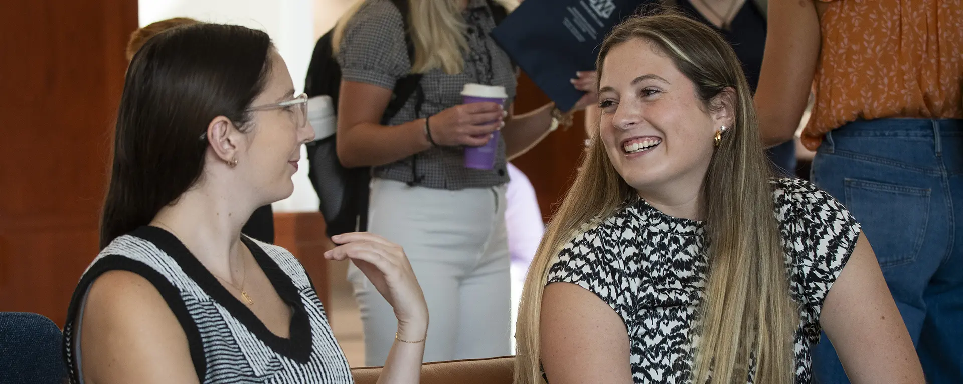 Two students smile while sitting in student commons. 