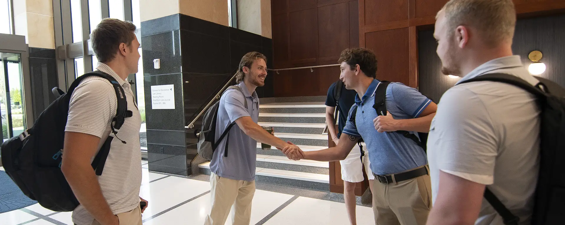 Students in a group and chat in the law school lobby.