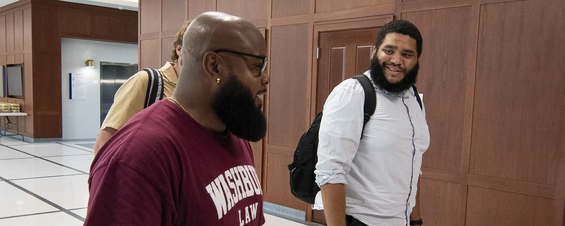 Two law students smile and chat while walking.