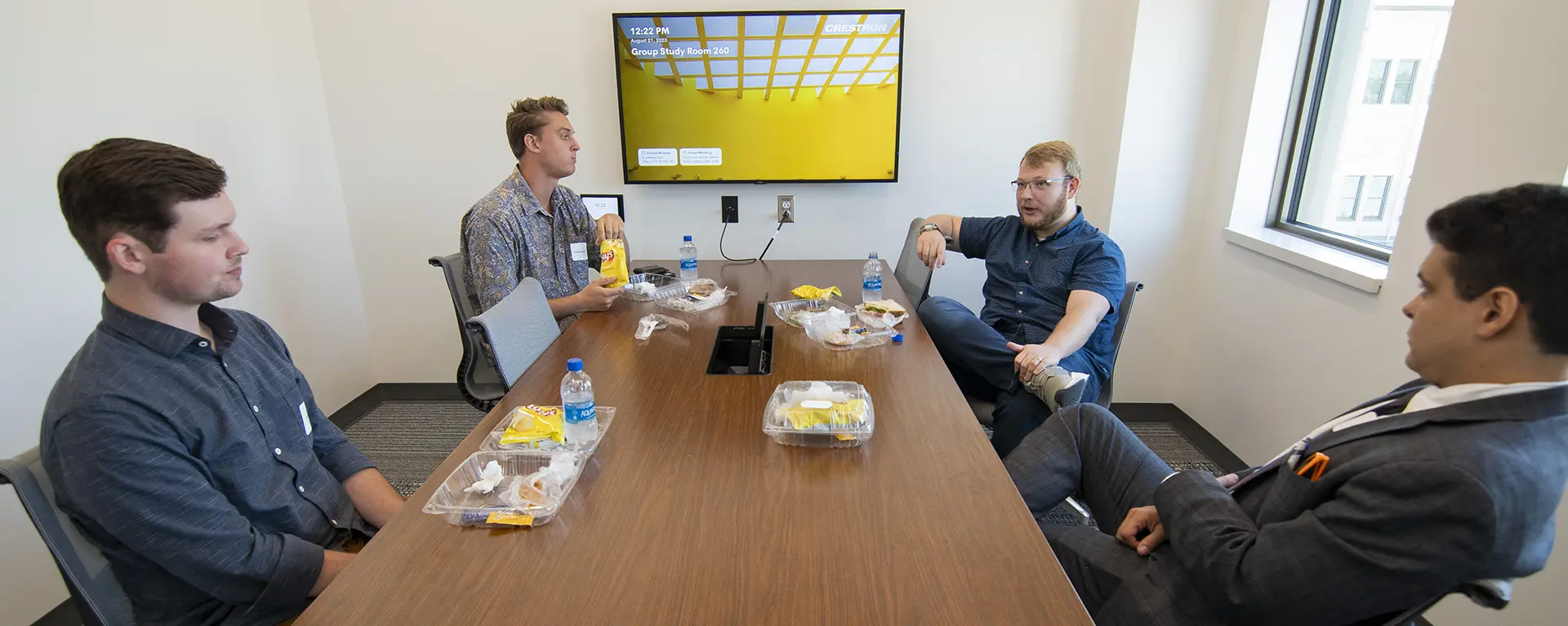 Students chat in their mentoring groups in a library study room.