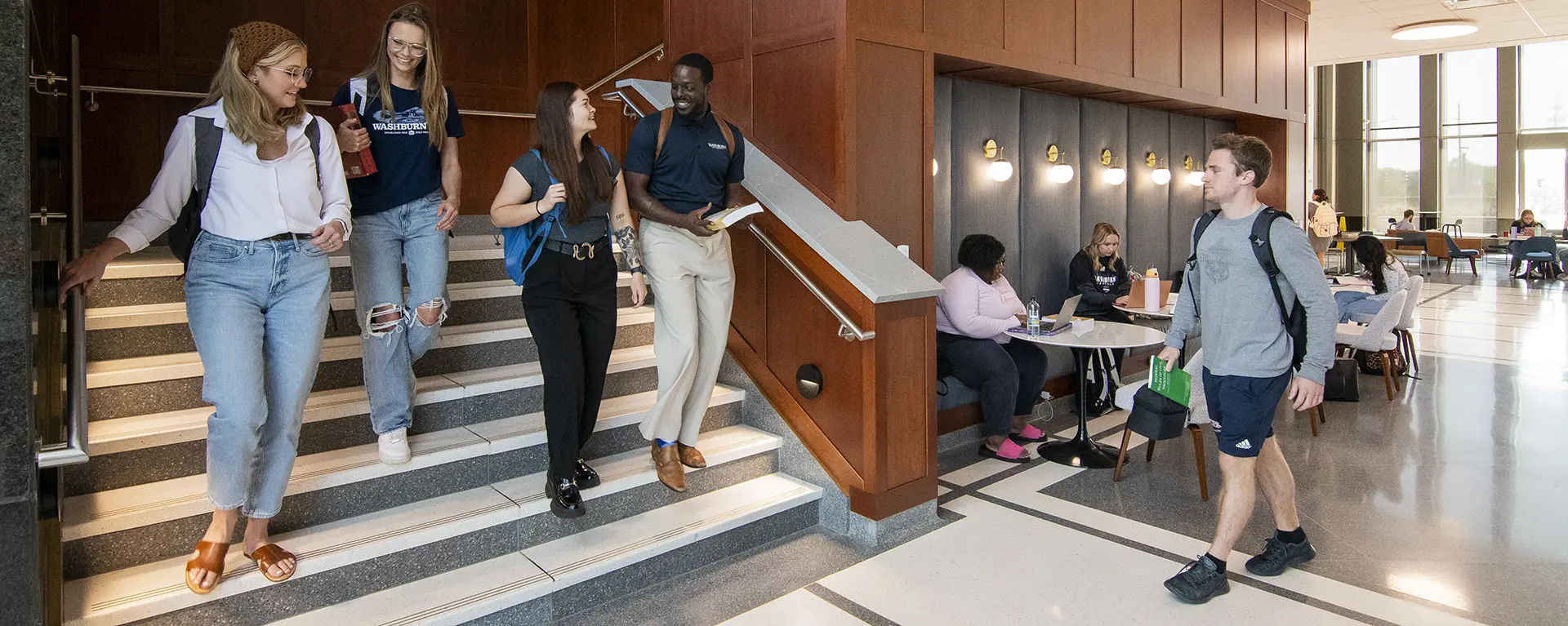 Students walking downstairs in lobby of Dole Hall. 