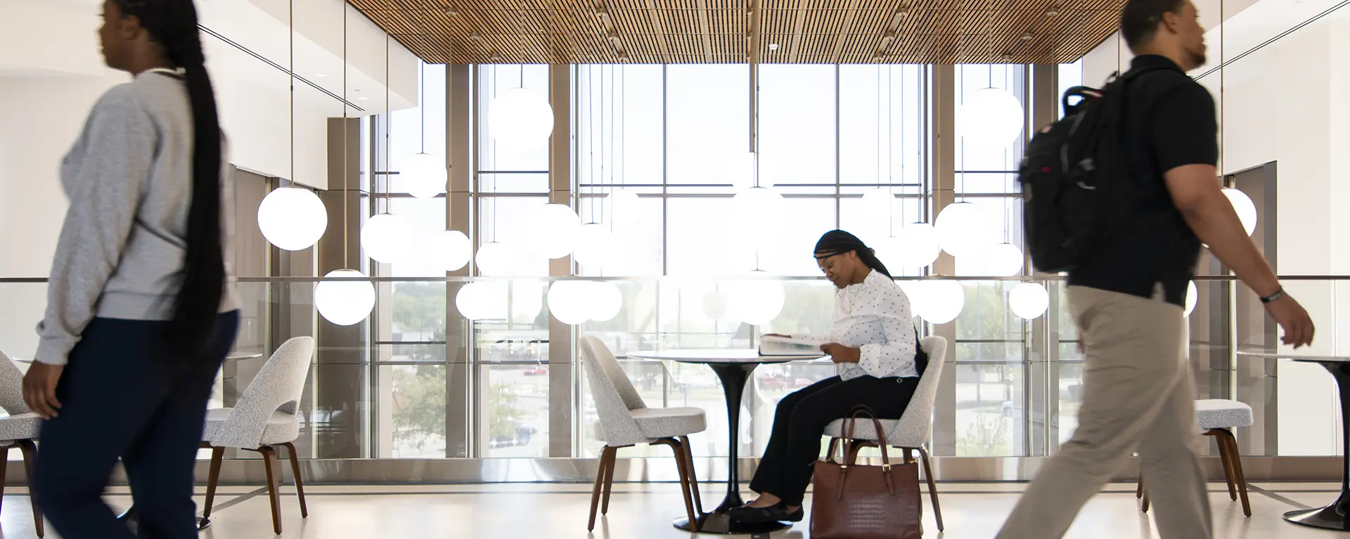 Student studying on second floor of Dole Hall while other students walk by. 