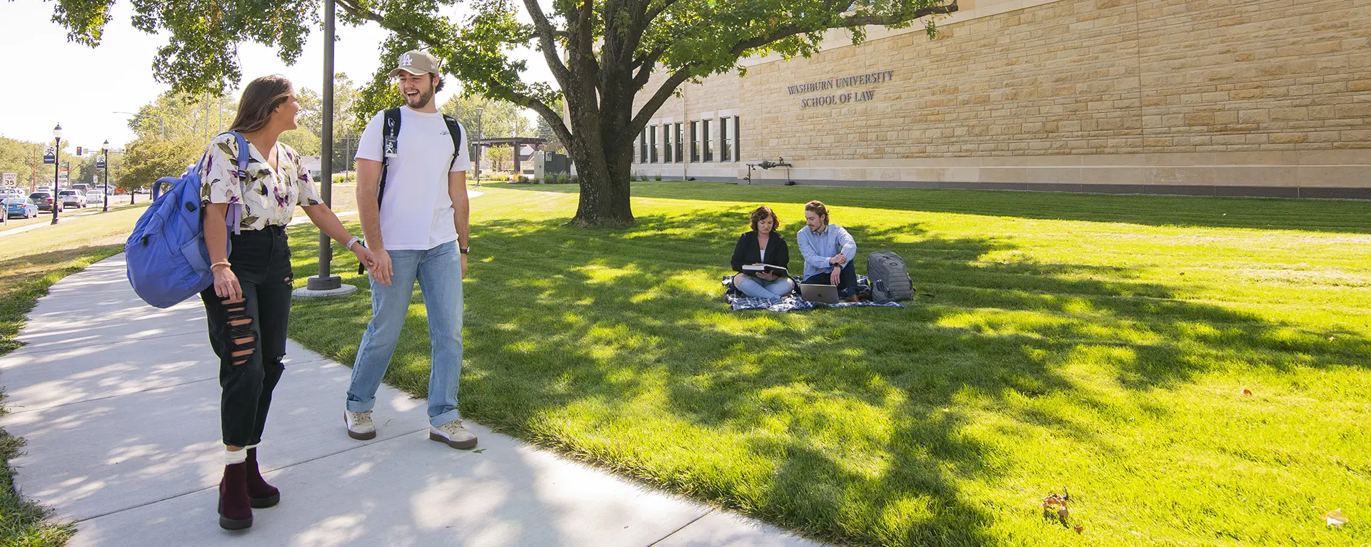 Two students walk outside on a sunny day. 