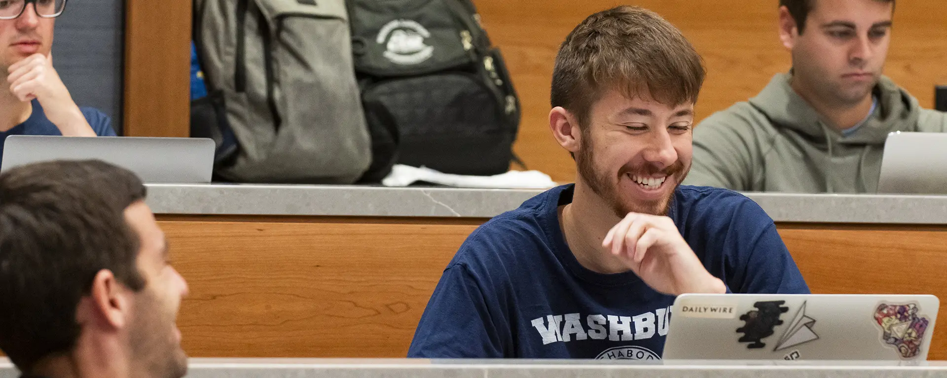 A student smiles while taking notes in class.