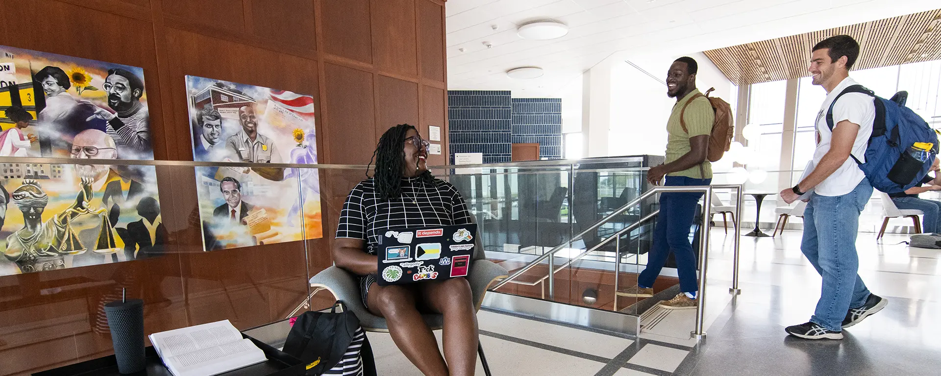 A student studies while two students smile while walking by in the law school.