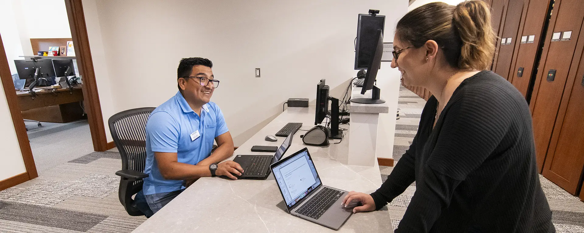 An IT professional helps a law school student with their computer.