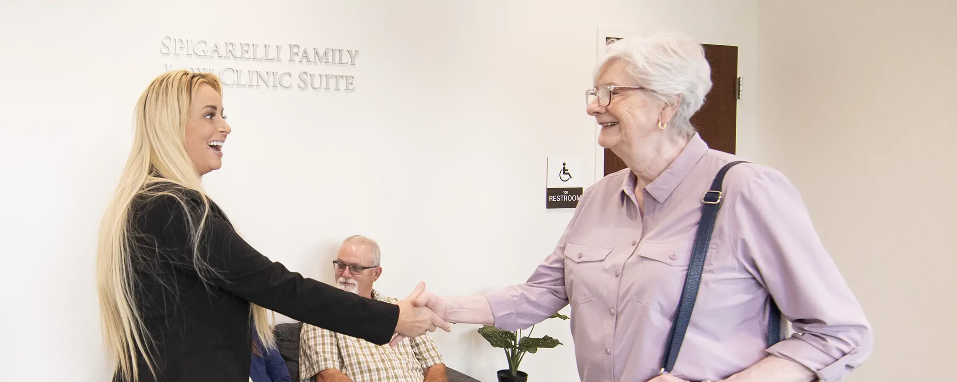 A law clinic student greets a client with a handshake.