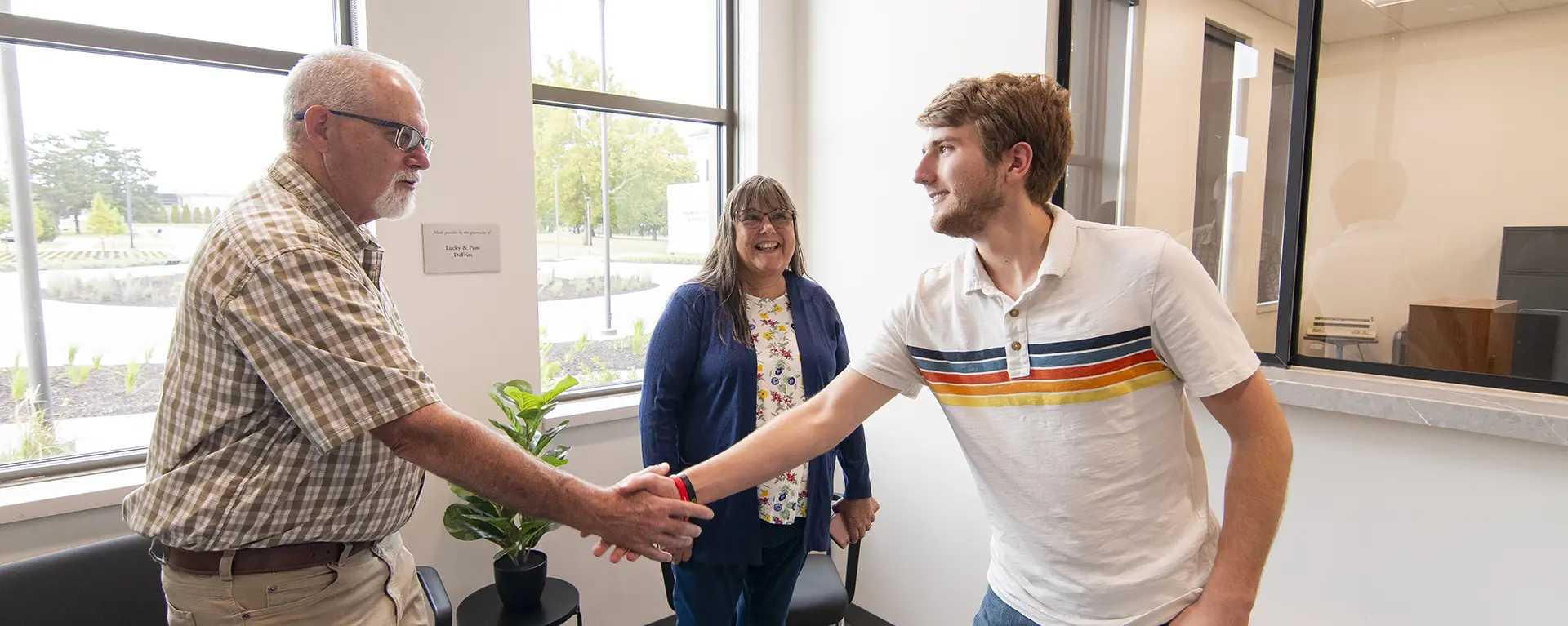 A law clinic worker shakes the hand of a client.