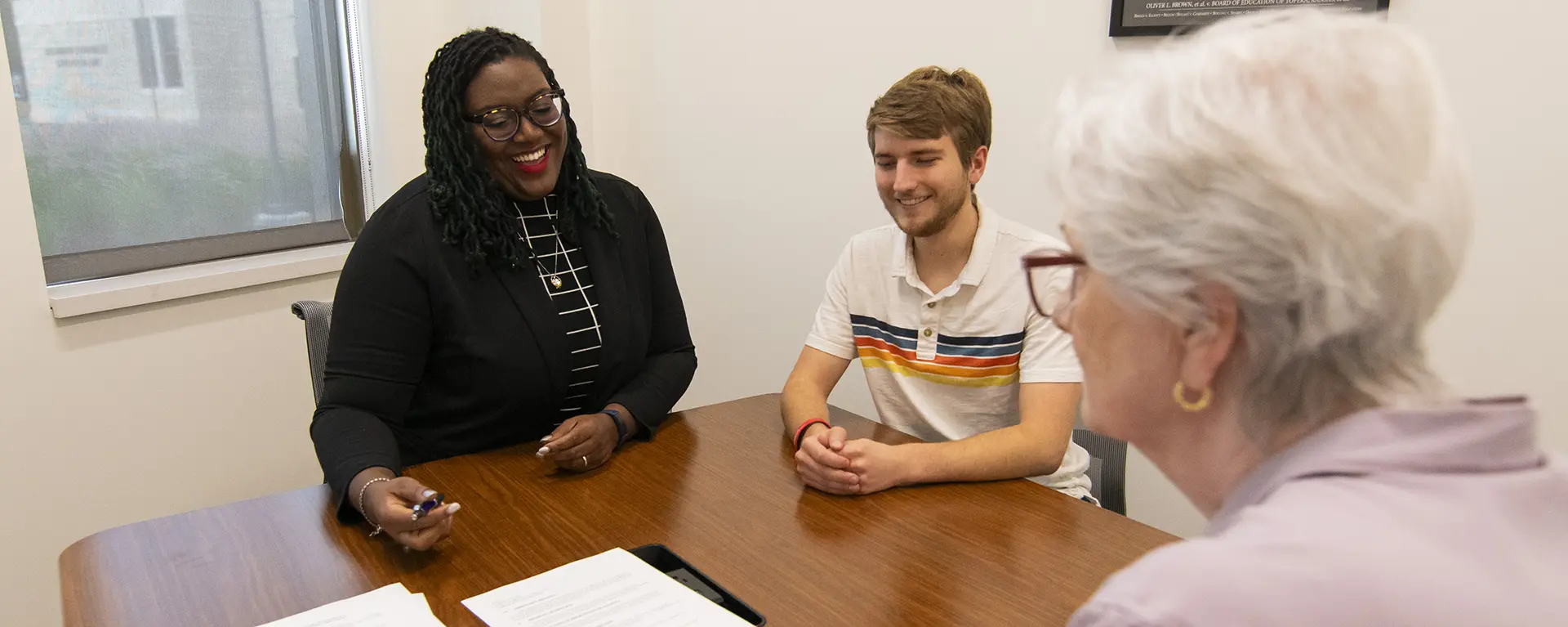 Two students go over a piece of paper with an older woman.