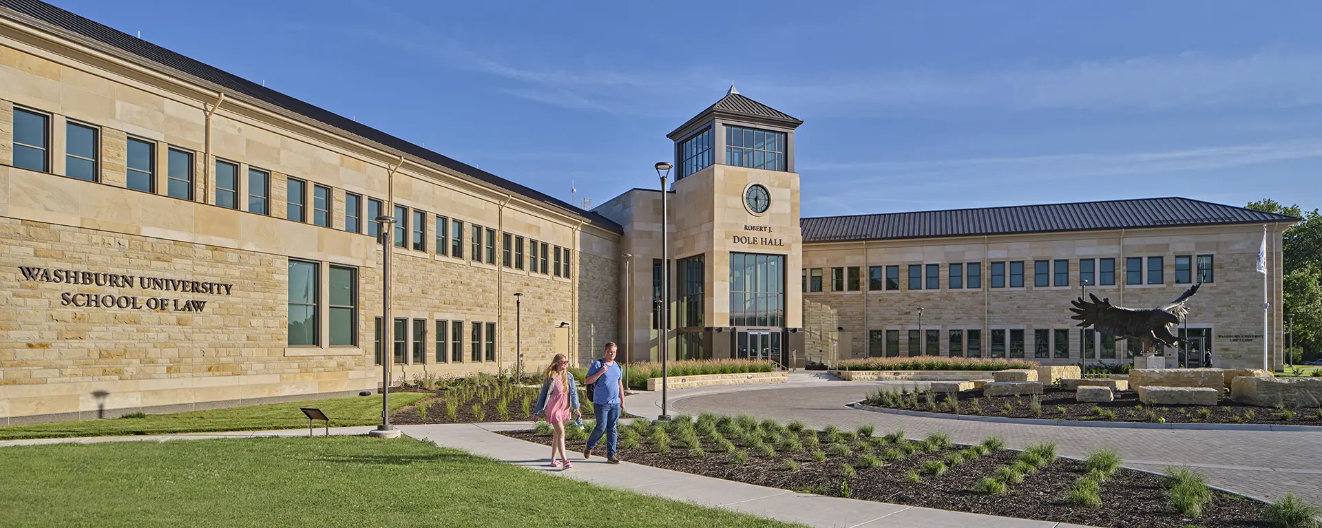 Law school students walk along the sidewalk in front of Robert J. Dole Hall.