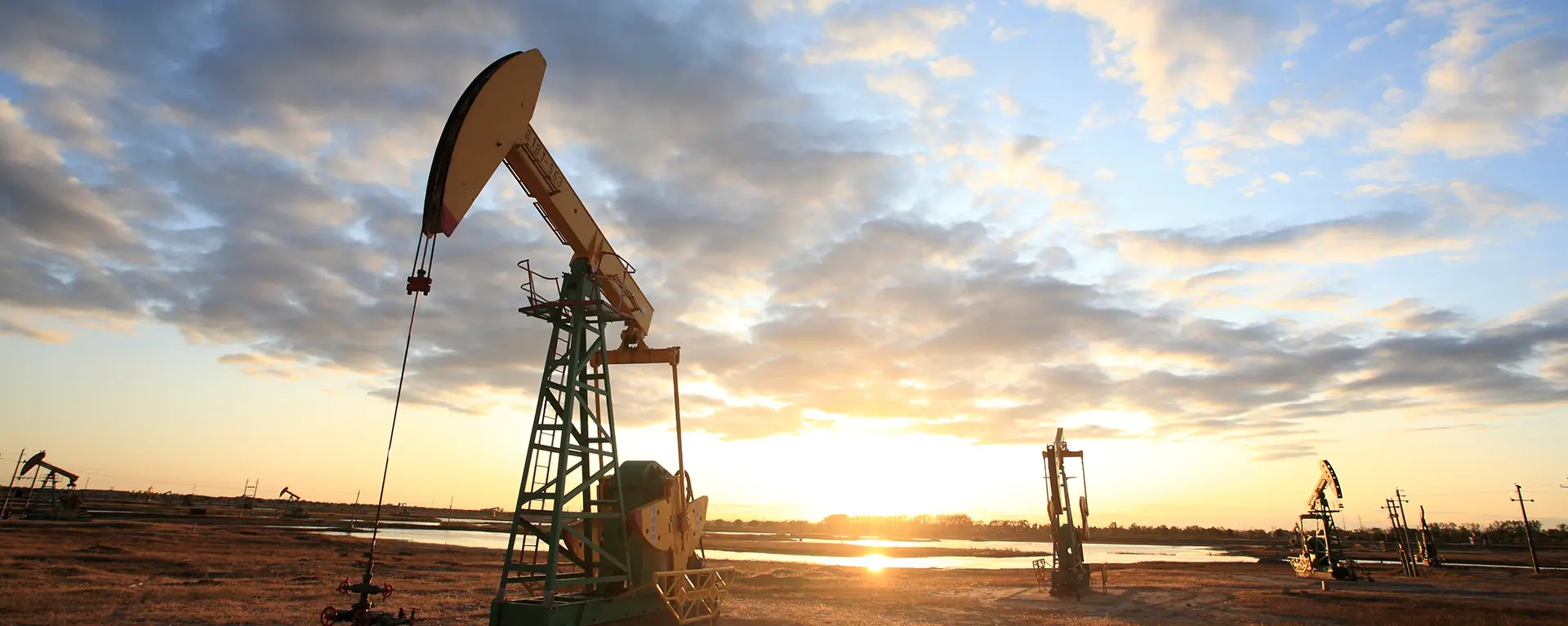 A field with oil derricks at sunset. 