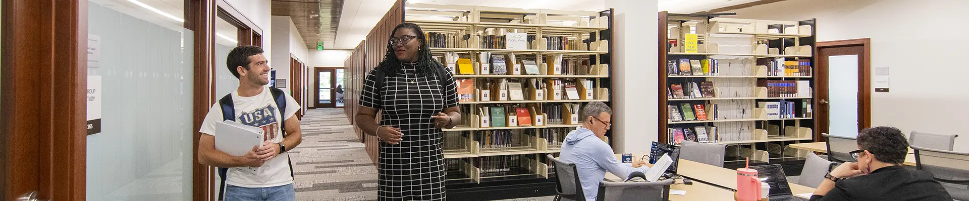 Students talk while walking through the law library.