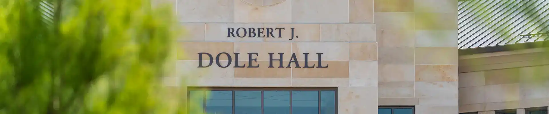 SOL building north entrance sign with unfocused trees in foreground