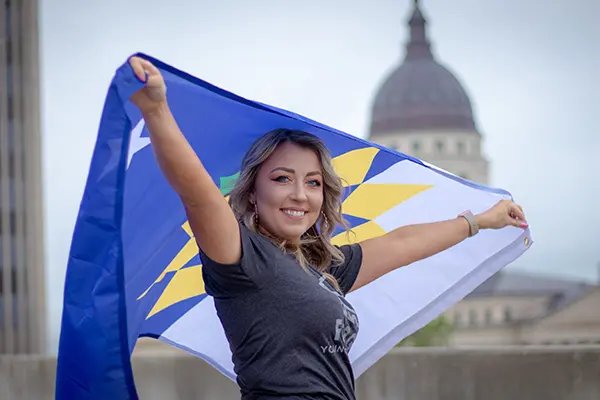 Woman waving Topeka flag in front of capitol building