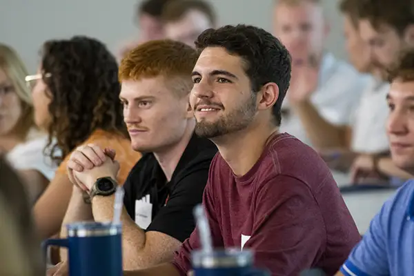 student in class seated and smiling