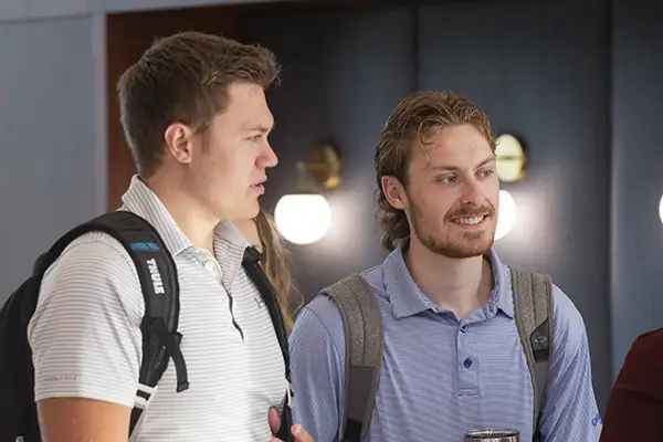 A student smiles while standing in a group chatting.