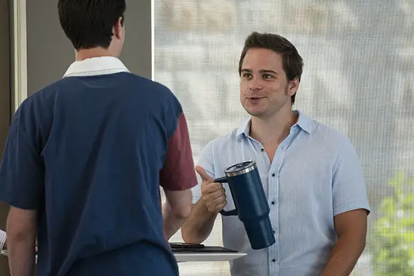 A law student gestures while holding a coffee thermos and talking.