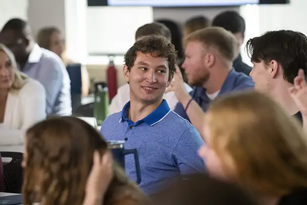 Students smile in full classroom. 