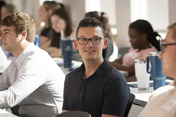 A law student smiles while paying attention in class.