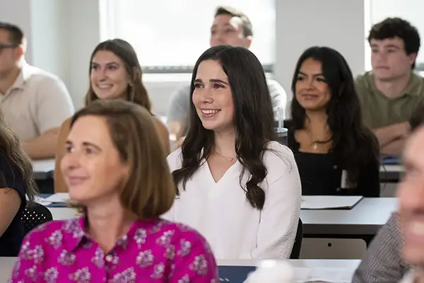 A law student smiles while paying attention in class.