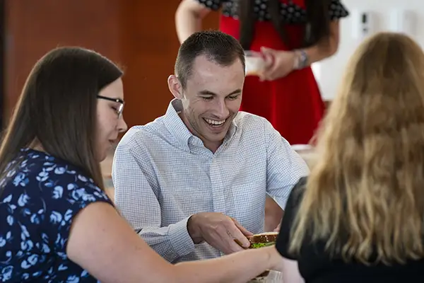 A student smiles while looking down at paperwork.