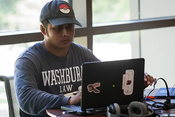 A student studies on his laptop at a table in the reading room. 