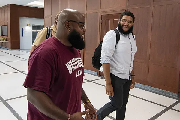 Two students chat while walking through Dole Hall. 