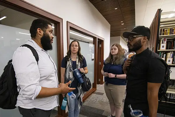 A group of students chat while touring the library.