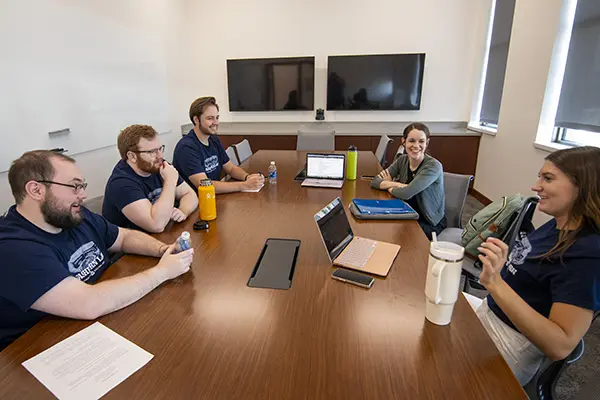 A group of students talk while in a conference room.