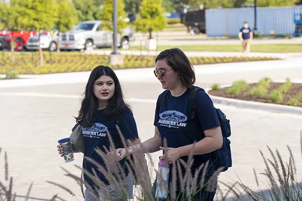 Two students walk in the Dole Hall circle drive. 