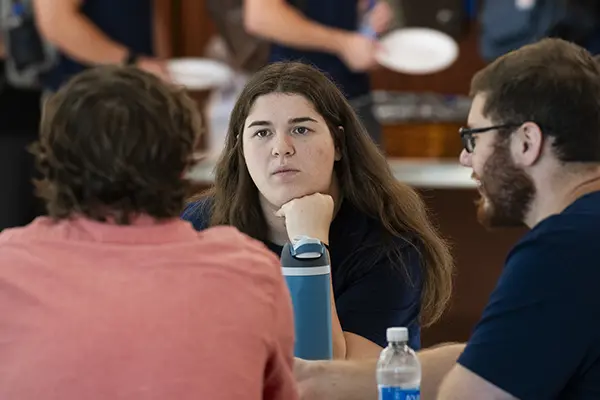 Three students have a discussion between classes. 