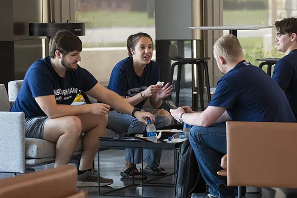 A small group of students sit in the student commons chatting between classes. 