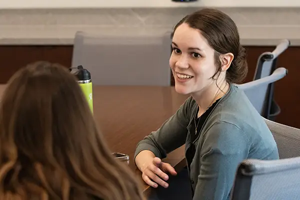 A student smiles and chats with another student.