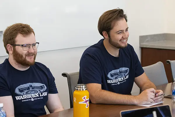 Two students smile while meeting with their mentor group.