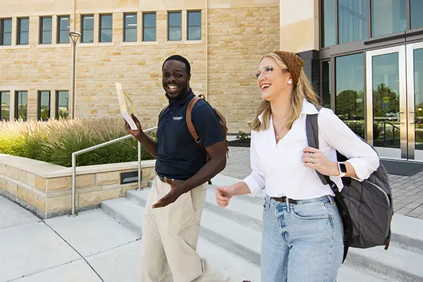 Two students walking out of Dole Hall chatting. 