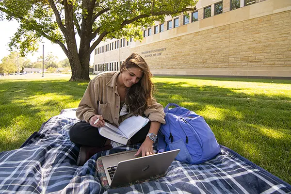 Student studying outdoors on blanket. 