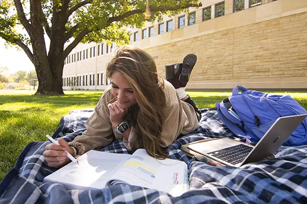 A student studies on a picnic blanket outside Dole Hall.