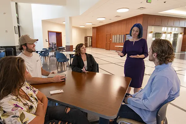 A law professor talks with a group of students in the law school lobby.