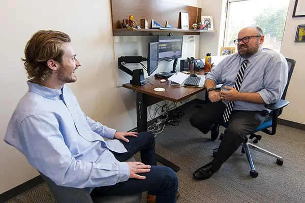 student and professor sitting in office talking