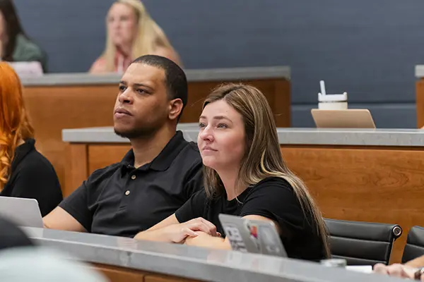 Two students sitting in appellate courtroom look toward front of room. 