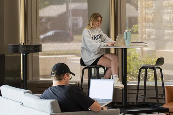 lobby with two students sitting at tables with laptops