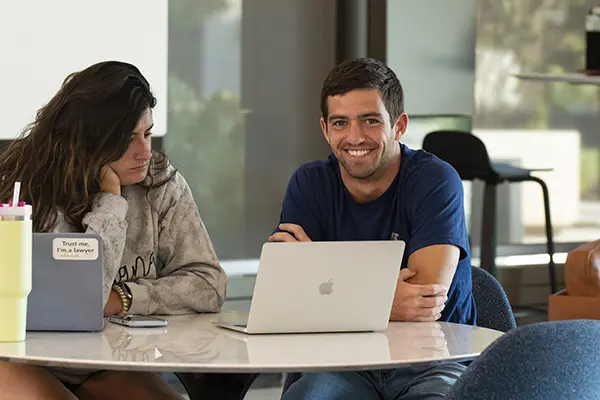 Two students work together at table in student commons. 