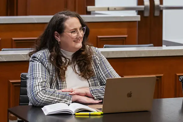 A student smiles while dressed professionally in one of the courtroom classrooms.