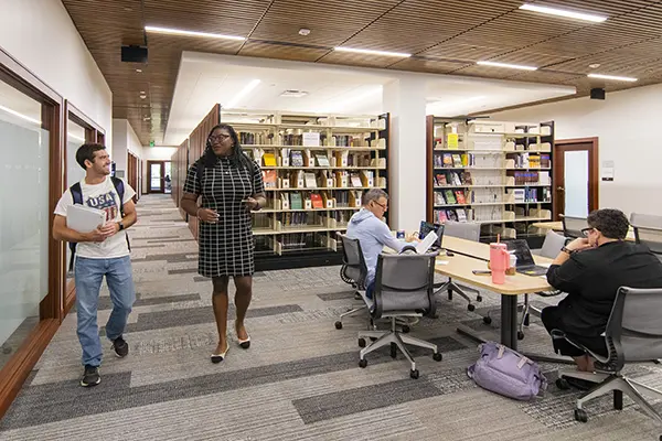 Students chat while walking through the library.