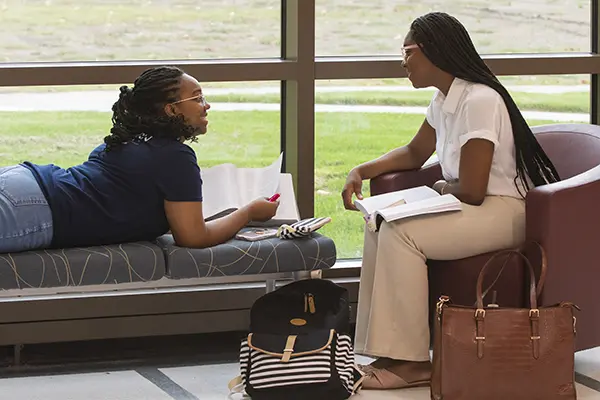 Two students study next to a window in Dole Hall.