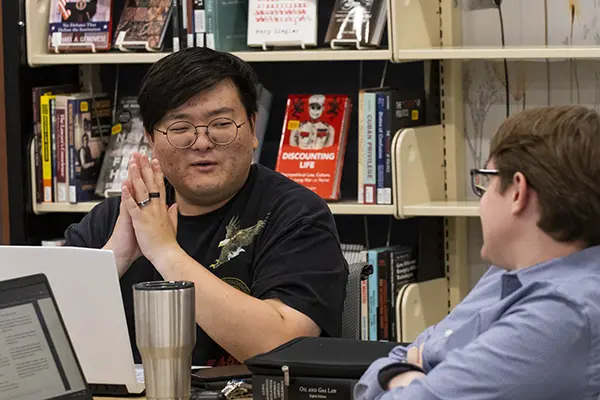 Two students chat while studying in the library.