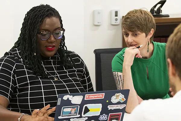 A law clinic student and faculty advisor study details of a case on a laptop.