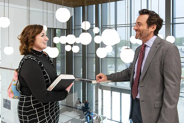 student and professor talking in balcony area of SOL building lobby