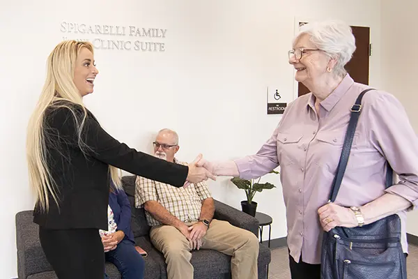 A law student shakes the hand of client in the law clinic waiting room.