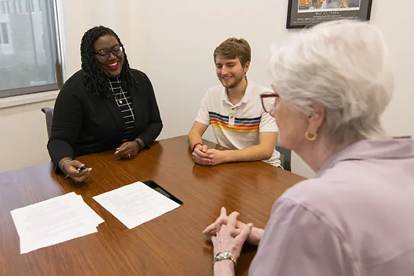 Two law students smile while talking with a law clinic client.